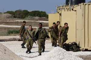 Israeli soldiers, stationed at an Iron Dome rocket shield battery site, run for cover as a siren is sounded warning of incoming rockets near Ashdod